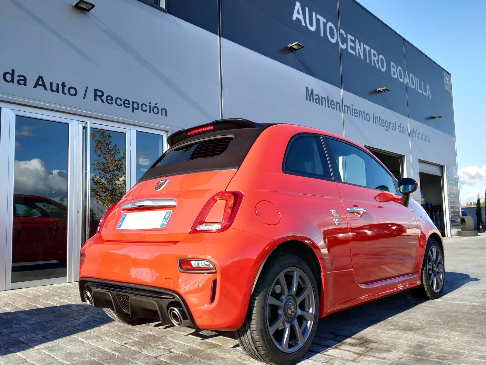 Abarth naranja aparcado junto a la entrada del taller