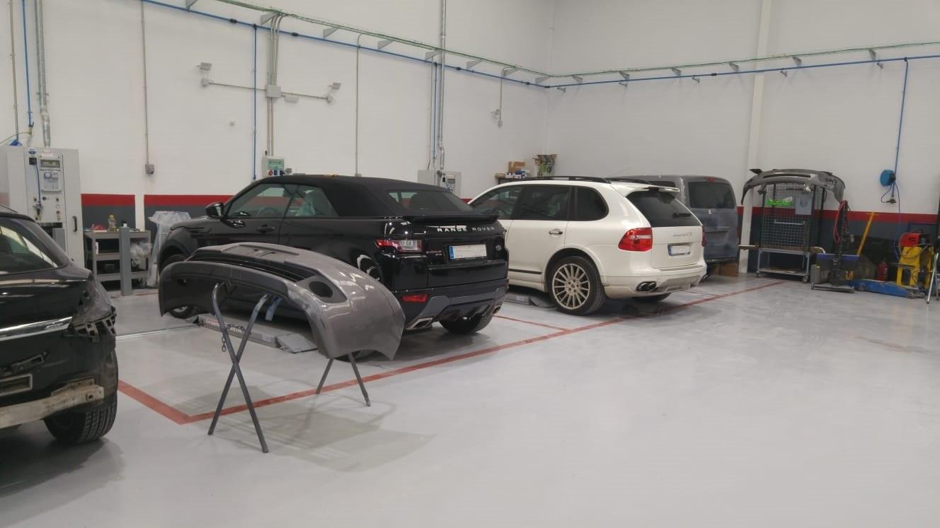 Zona de carrocería del taller, amplia y luminosa, con varios coches en reparación