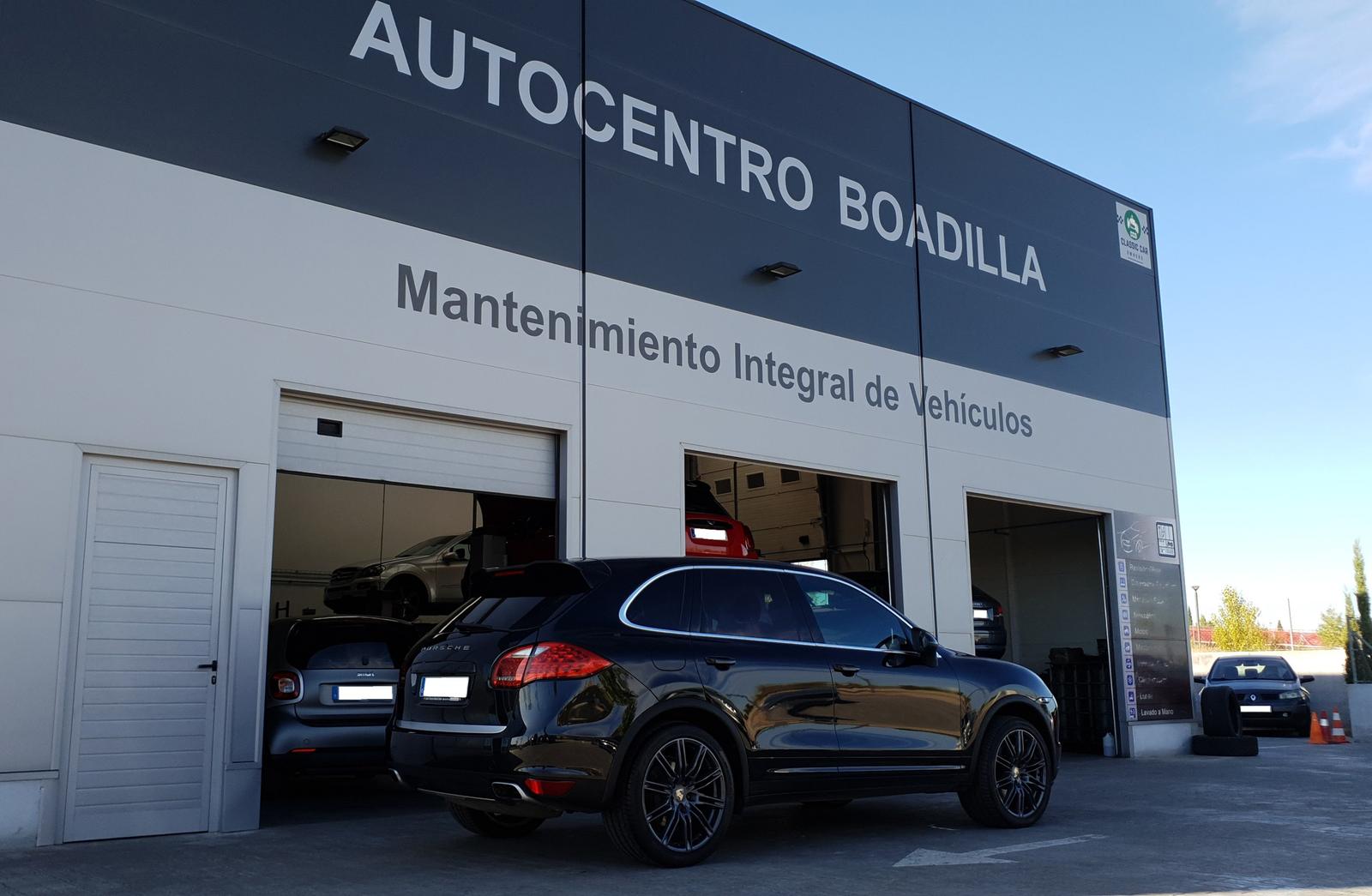 Porsche negro a la puerta de uno de los portones del taller